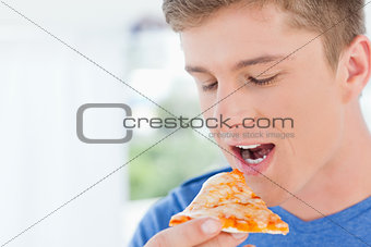 A man with a piece of pizza near his mouth 