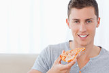 A man sitting as he holds a slice of pizza 