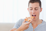 A man looking at the slice of pizza he is about to eat