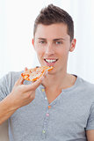 A smiling man holding pizza as he is about to eat