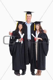 Full length of three friends graduate from college together