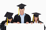 Three students having graduated holding blank sheet and looking 