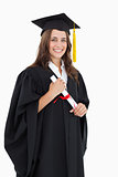 A smiling woman with her degree as she looks at the camera