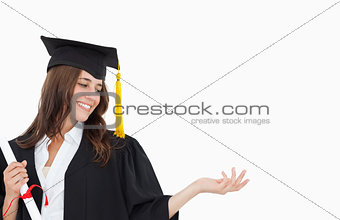 A smiling woman with a degree as she opens out her other hand