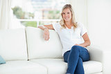 A woman smiling as she relaxes on the couch with her legs crosse