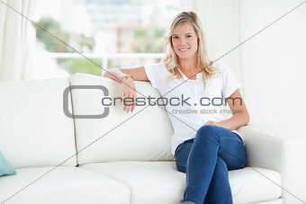 A woman smiling as she relaxes on the couch with her legs crosse