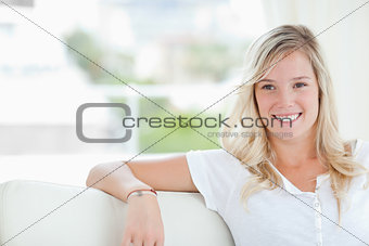 A woman smiling as she sits on the couch and looks to the side