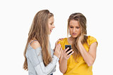 Upset young woman holding her cellphone consolded by her friend