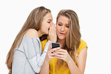 Student whispering to her friend who's texting on her phone