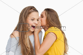 Young woman whispering to her friend