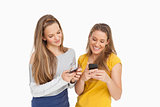 Two young women texting on their cellphones