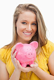 Portrait of a young blond woman holding a piggy-bank 