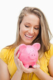 Close-up of a blond woman looking a piggy-bank
