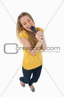 Fisheye view of smiling blonde singing with a microphone