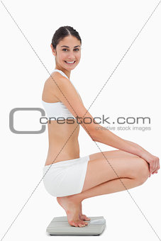 Slim young woman sitting on a scales