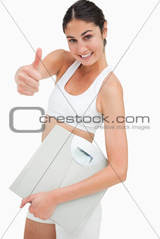 Portrait of a slim woman holding a scales the thumb-up