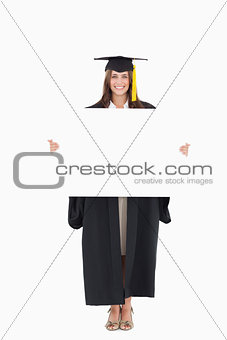 Full length of a woman holding a blank sheet in front of her as 