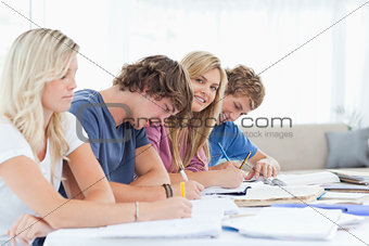 A smiling girl looks at the camera while she sits with students