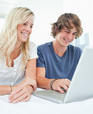 A smiling couple sit together as they surf the internet
