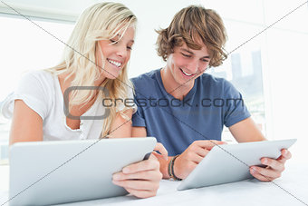 A man and woman both using their tablets 