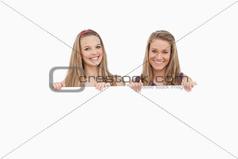 Close-up of two young women holding a blank sign