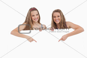 Portrait of young women holding and pointing a blank sign