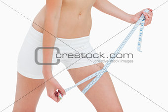 Close-up of a slim woman measuring her thigh