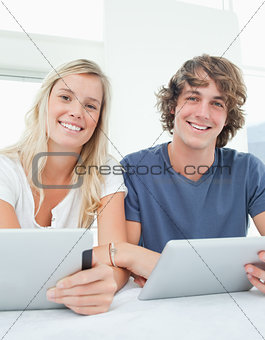 A couple with tablets smile and look at the camera