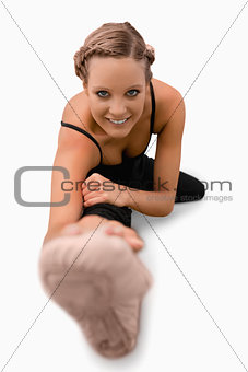 Smiling woman doing stretches on the floor