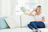 A smiling woman sitting on the couch as she talks on her phone