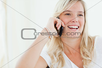 Close up of a woman laughing on her phone as she looks to the si