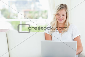 A woman smiling as she looks at the screen of the laptop she is 
