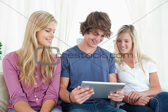 Three friends sit together as they look at a tablet pc 