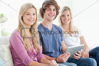 three siblings sit together as they use a tablet and look at the