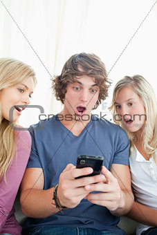 Shocked friends look at the man's phone