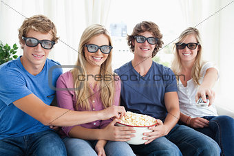 Friends smiling as they eat popcorn and watch a 3d movie