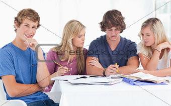 A group of students sitting together as they all study as one sm