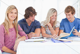 A study group working hard as one girl smiles and looks at the c