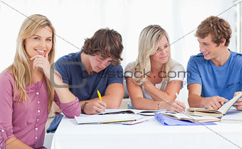 A study group working hard as one girl smiles and looks at the c