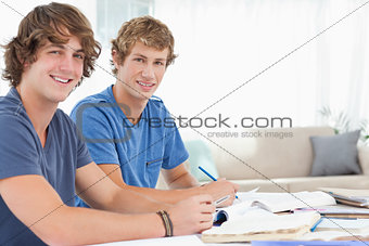 Side view of two students looking into the camera and smiling 
