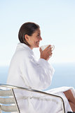 Side view of woman in bathrobe drinking coffee