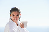Smiling woman in bathrobe with a cup of coffee