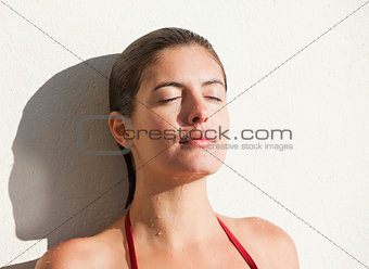 Woman enjoying the sun while leaning against a wall