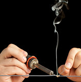 Technician soldering two wires together on a black background.