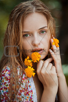 Portrait of a blonde girl with green eyes holding yellow flowers