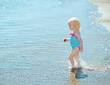 Baby girl walking into sea
