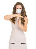Young woman in mask showing stop gesture