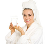 Happy young woman in bathrobe holding glass of water