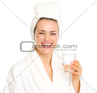 Smiling young woman in bathrobe with glass of water