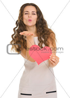 Smiling young woman showing valentine's day cards and blowing ki